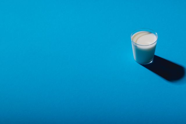 High angle view of milk glass over blue background with copy space. unaltered, food, drink, studio shot and healthy eating.