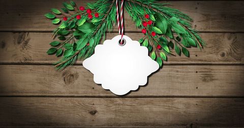 gift tag hanging against rustic wooden backdrop with christmas tree branches and red berries. ideal for festive greeting cards, seasonal offers, holiday crafts, social media posts celebrating christmas cheer or promotional materials for retail gifts.