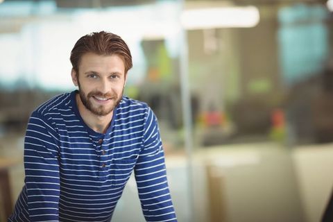 Business professional leaning over desk in striped shirt, copy space