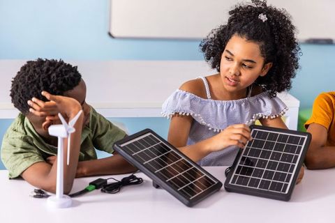 Elementary students learning renewable energy with solar panels and wind turbine hands-on