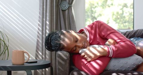 Young woman relaxing on sofa with dog cushion in cozy room