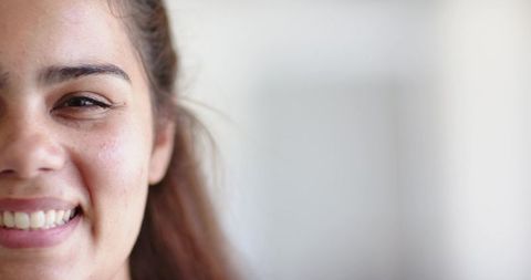 Smiling young woman showing teeth freckled cheek bright airy portrait with copy space