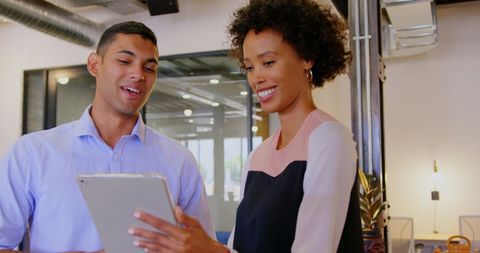 Smiling Colleagues Collaborating on Tablet in Modern Office Environment