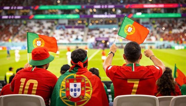 Cheering portugal fans waving flags in stadium celebrating international football match