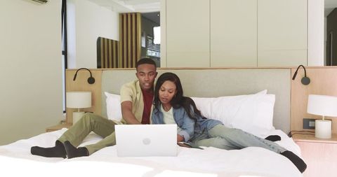 Couple using laptop in modern bedroom setting