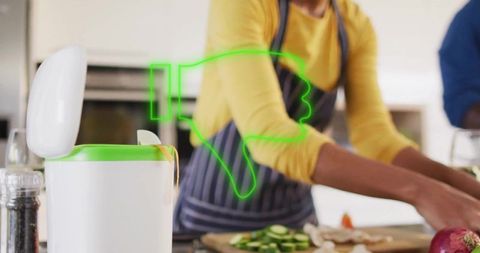 Home cook chopping cucumbers on cutting board beside green-rim bin with thumbs-down icon