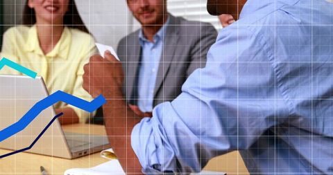 Business Team Collaborating Over Data and Charts with Man Presenting Paper at Table