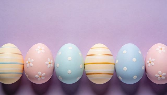 Pastel easter eggs decorating lavender background with daisies, polka dots and stripes