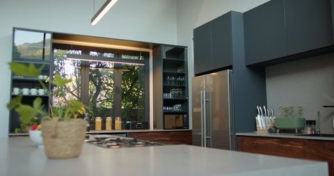 Anchoring Kitchen Island Featuring Gas Cooktop, Woven Planter and Garden Window View