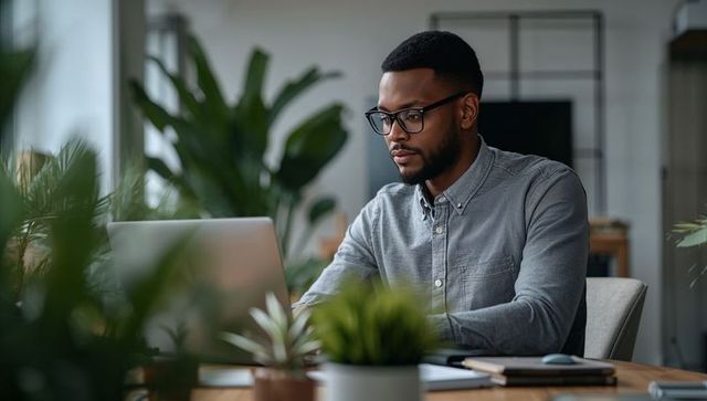 Man working on laptop in biophilic home office focusing on remote work productivity