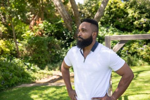 Confident African American Man Posing in Lush Backyard Garden
