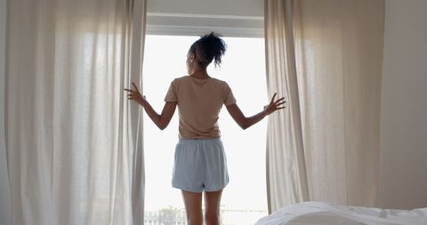 Woman Opening Curtains in Tranquil Bedroom Setting