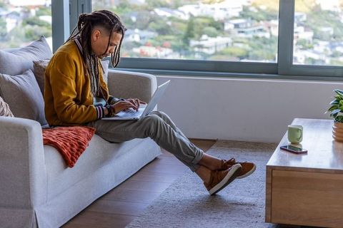 African american professional working remotely on laptop in modern cozy living room