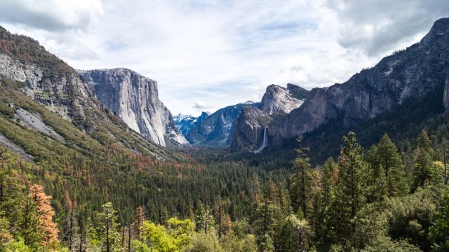 Picture capturing the stunning Yosemite Valley featuring impressive granite cliffs, lush forests, and cascading waterfalls. It is ideal for use in travel promotions, nature documentaries, environmental campaigns, and outdoor adventure advertisements.