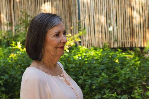 Elegant Senior Woman in Sunlit Backyard Showing Tranquility