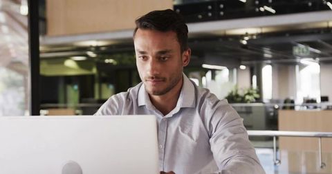 Focused Professional Working on Laptop in Modern Open-Plan Office
