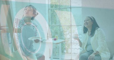 Young artist painting in home studio with mentor coaching and casual coffee break