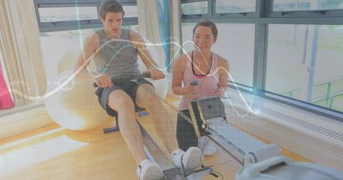 Young couple rowing together with fitness data overlay for smart cardio training partners