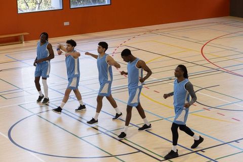Basketball Team in Synchrony on Gym Court Wearing Blue Uniforms