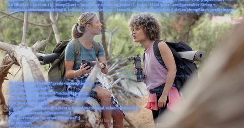 Female hikers talking on trail with code overlay blending outdoor adventure and technology
