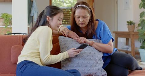 Asian Mother and Daughter Relaxing Together with Smartphone at Home