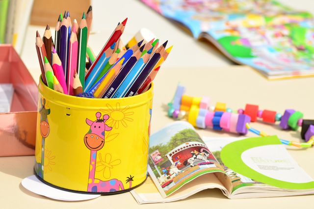 Shows a container holding colorful pencils on a crafting table, indicating a fun and engaging activity area for children. Can be used for educational and creative campaigns, craft activity promotions, back-to-school advertisements, and articles on encouraging children's creativity.