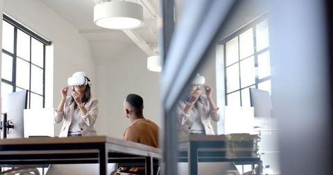 Businesswoman Using VR Headset Collaborating with Colleague in Office