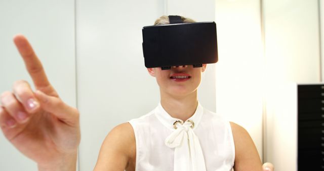 Young woman engaged in an immersive experience with virtual reality headset. She is pointing and interacting with the virtual environment. Perfect for use in advertisements, articles, or presentations about cutting-edge technology, virtual reality, modern innovations, or gaming.