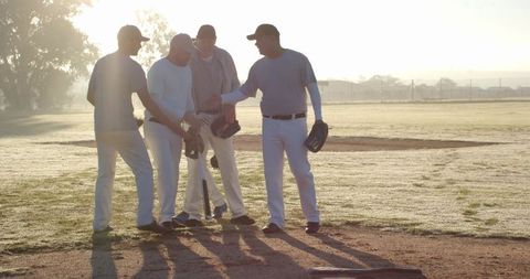 Sunrise Backlit Baseball Team Huddling on Dewy Field Preparing for Game Warmup