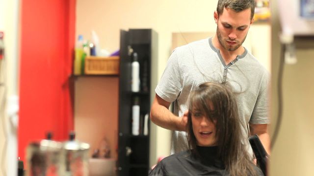 Hairdresser focused on styling a woman's hair in a contemporary salon. Perfect for advertising salon services, fashion magazines, or articles on beauty trends and professional hairstyling techniques.