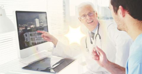 Experienced doctor mentoring junior colleague with technology