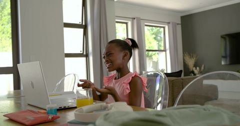 Frustrated black girl studying at laptop in bright modern home dining area with juice