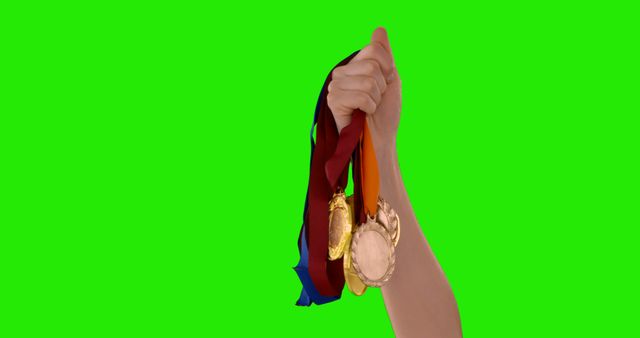 A hand with medals is raised against a green screen for visual effects or celebratory purposes. - Download Free Stock Photos Pikwizard.com