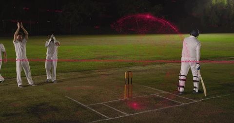 Night cricket batsman standing at crease with bowler follow-through and magenta motion trail