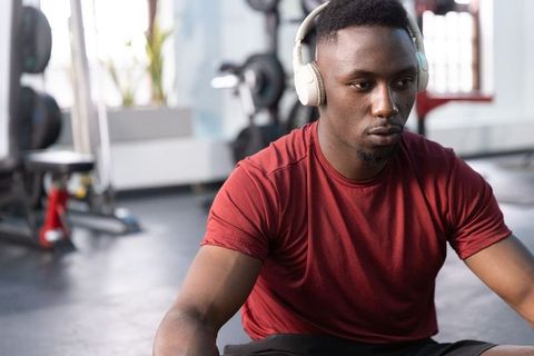 Focused african american athlete wearing headphones sitting in gym preparing workout