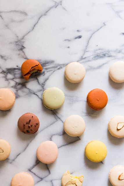 Assorted colorful macarons displayed on a chic marble surface, showcasing their variety of flavors and vibrant hues. Perfect for use in culinary blogs, dessert menus, food festivals advertising, and gourmet dessert promotions to evoke a sense of sophistication and delight.