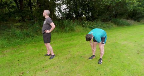 Two men exercising in nature on grassy meadow
