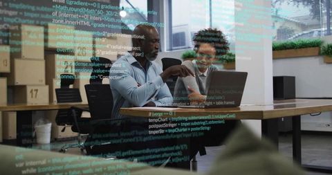 Senior mentor guides young professional at office desk