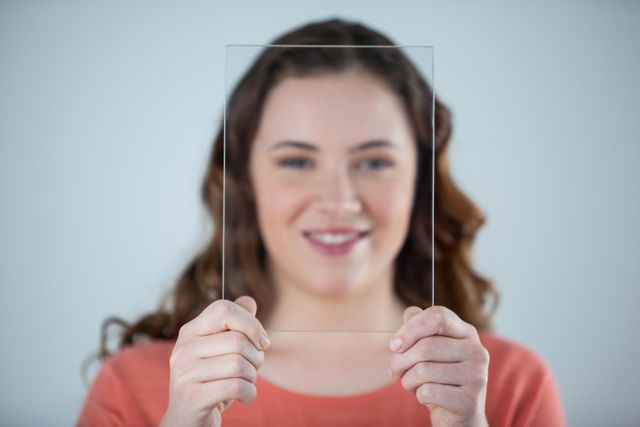 Portrait of smiling woman holding a glass sheet against her face