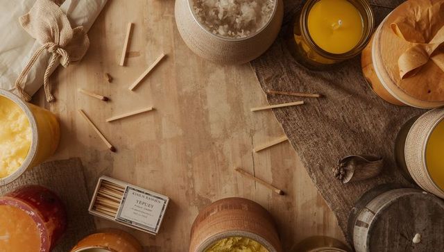 Rustic candle arrangement with scattered matches, matchbox, amber jars on wooden tabletop