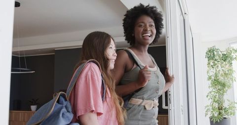 Excited friends entering hotel room admiring balcony view