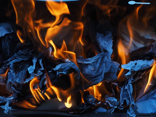 Burning paper enveloped by intense flames shows concept of destruction, heat, danger. This visual is useful for illustrating fire-related topics, emergency situations, fire safety campaigns, or abstract art in creative projects depicting chaos and devastation.