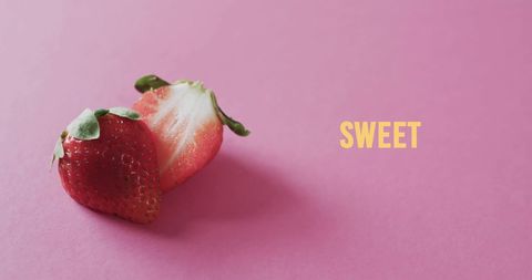 Halved strawberries on pink background with sweet text