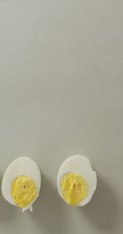Two halves of hard boiled eggs on minimalistic grey surface