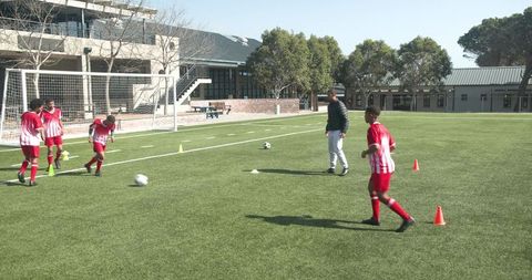 Youth Soccer Team Practicing Drills on School Field with Coach