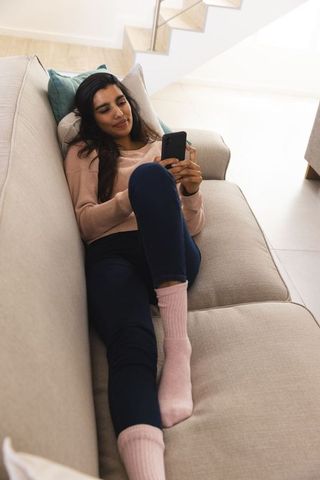Relaxed Woman Enjoying Leisure Time on Couch at Home with Smartphone
