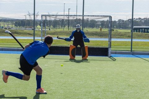 Teenage Field Hockey Striker Aiming for Goal Against Skilled Goalkeeper