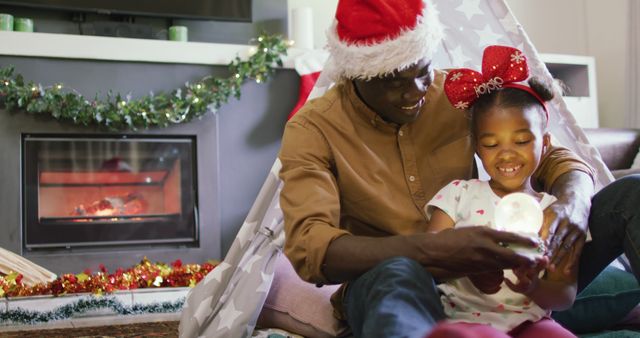 Father and daughter smiling and enjoying a festive moment in a cozy living room with Christmas decorations. Perfect for illustrating family bonding, holiday cheer, and seasonal celebrations in promotional materials, holiday greeting cards, and social media posts.