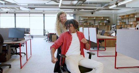 Joyful colleagues spin on chair celebrating team bonding
