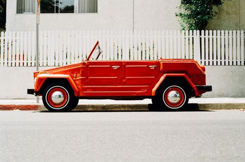 Vintage red convertible car by picket fence